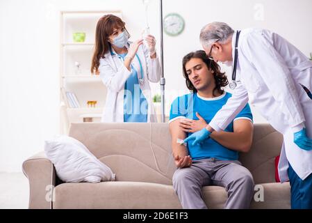 Two doctors visiting sick man at home Stock Photo