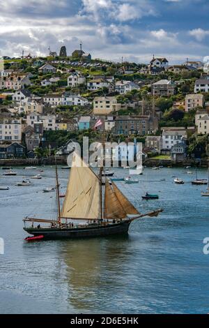 Old ketch leaving Fowey Harbour with Poltuan town behind Cornwall England Stock Photo