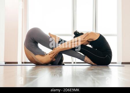 Two women doing yin yang pose practicing yoga exercise in yoga