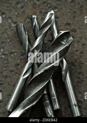 Old worn-out drill bits over rusty metal background Stock Photo