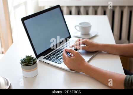 Blond hair young woman working at home on laptop. Woman sitting at the table at home working using computer laptop. Coronvirus concept. Stay home. Co Stock Photo