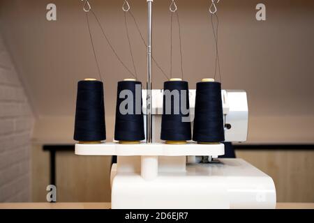 Black thread bobbins on modern overlock white sewing machine, professional sewing machine Stock Photo