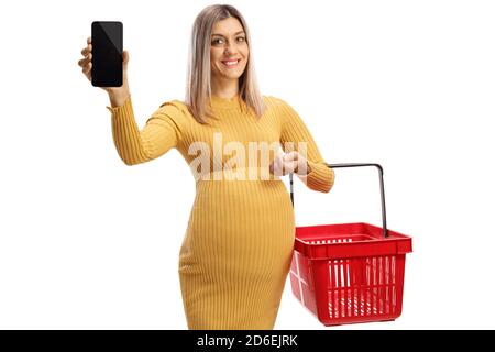 Smiling pregnant woman holding a shopping basket and showing a smartphone isolated on white background Stock Photo