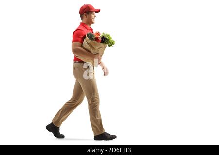 Full length profile shot of a delivery man walking with a bag of groceries isolated on white background Stock Photo