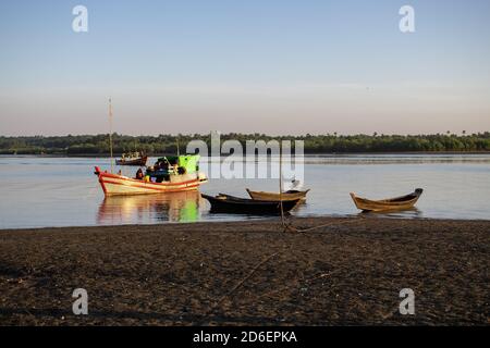 Chaung Thar, Myanmar - December 26, 2019: Traditional wooden boats by the shore of a river lit up by the sunset on December 26, 2019 in Chaung Thar Stock Photo