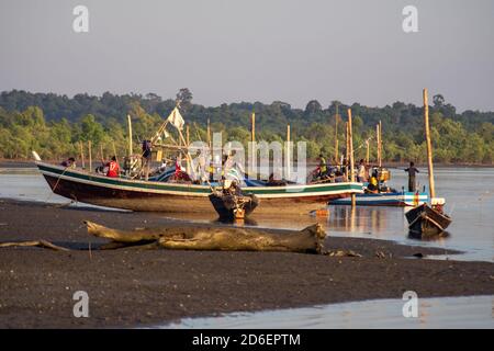 Chaung Thar, Myanmar - December 26, 2019: Traditional wooden boats by the shore of a river lit up by the sunset on December 26, 2019 in Chaung Thar Stock Photo