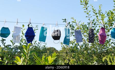 a lot of different colorful self made corona face masks out of fabric hanging on a clothesline for drying Stock Photo