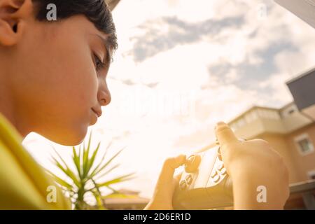 child flies with the drone with remote control in his hand in an urban setting playing with quadrocopter outdoors Stock Photo