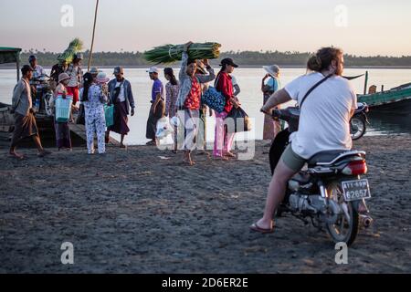 Chaung Thar, Myanmar - December 26, 2019: People disembarks from the local ferry and carries cargo ashore on December 26, 2019 in Chaung Thar, Myanmar Stock Photo