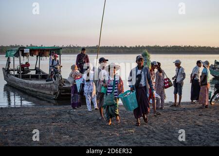 Chaung Thar, Myanmar - December 26, 2019: People disembarks from the local ferry and carries cargo ashore on December 26, 2019 in Chaung Thar, Myanmar Stock Photo