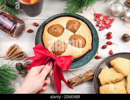A woman's hand holds a pie on a Christmas background. Stock Photo