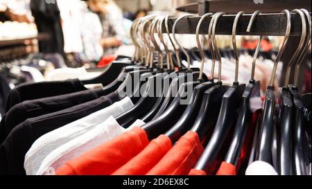 Close-up Modern fashionable women's clothing hangs on black plastic hangers in a department store of a clothing store. Online shopping for casual clot Stock Photo