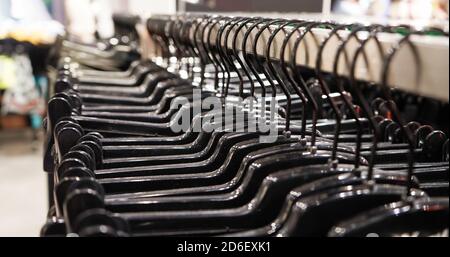 Close-up Modern fashionable women's clothing hangs on black plastic hangers in a department store of a clothing store. Online shopping for casual clot Stock Photo