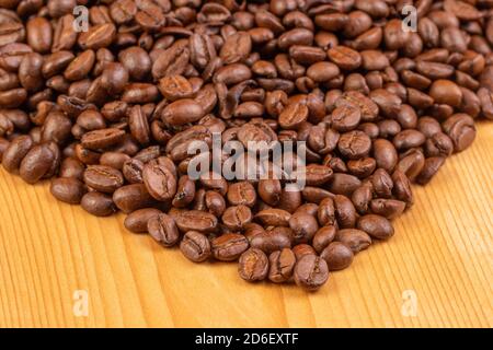 Closeup of roasted coffee beans lying on a wooden background. Macro. Stock Photo