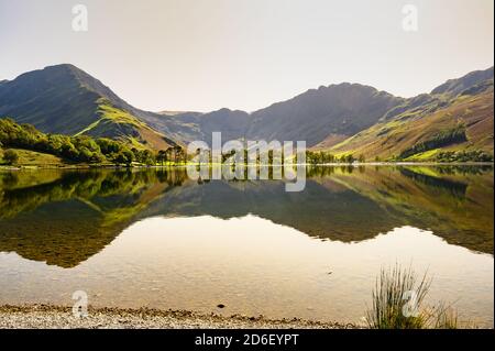 Hills and trees reflected in Buttermere Stock Photo