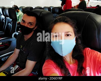 couple of travelers wearing masks on their faces in the cabin. Flights under the new rules of the coronavirus pandemic. Stock Photo