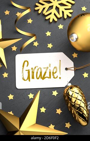 Christmas - Gift Tag with the Italian message 'Grazie!' (Thanks!) on a black stone background with gold colored christmas ornaments around. Stock Photo