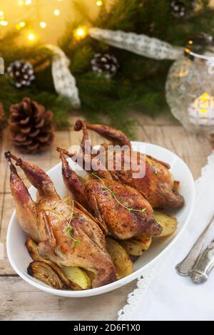 Baked quail with potatoes and onions on a festive background. Rustic style. Stock Photo