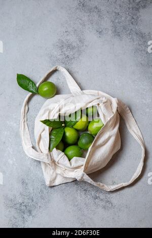 Ripe limes with fresh lime tree leaves in eco linen bag. top view. Stock Photo