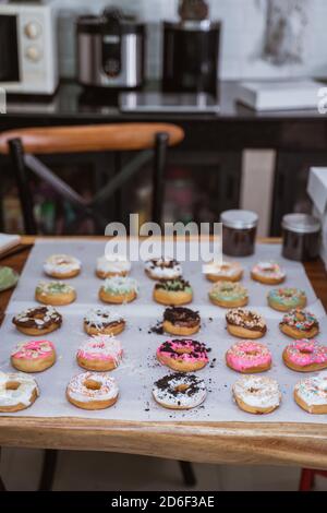 Assorted donuts with chocolate frosted, pink glazed and sprinkles donuts on the table Stock Photo