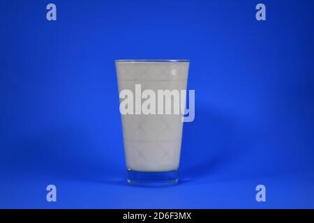 Shot of splashing milk from a cup on a blue background Stock Photo