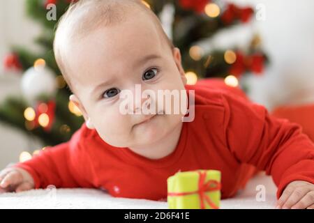 merry christmas christmas and happy new year, infants, childhood, holidays concept - close-up 6 month old newborn baby in red clothers on his tummy Stock Photo