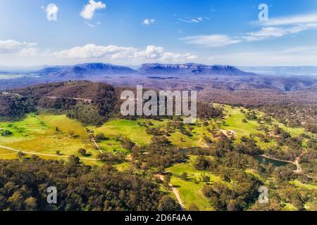 Capertee valley in aerial view above gumtree woods and green pastures between mountain ranges. Stock Photo