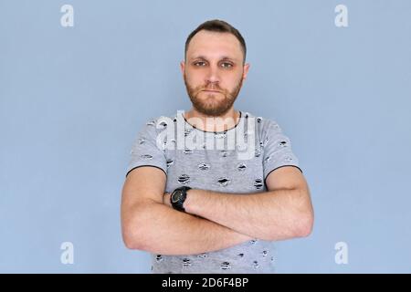 Portrait of real serious bearded man with crossed arms, gray background Stock Photo