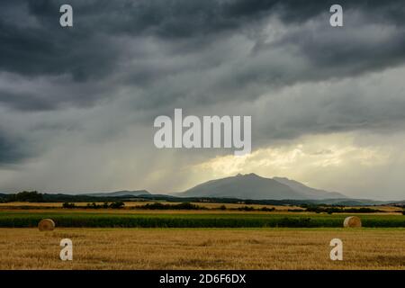 Dark rain clouds over field of harvested wheat. Stock Photo