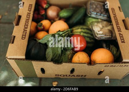 Close up of CSA farmers box full of produce on front porch Stock Photo