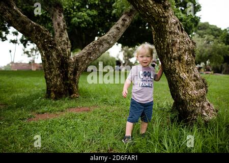 Two Year Old Posing Next to Tree in Park