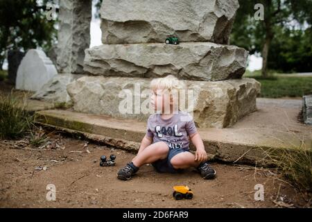 Two Year Old Sitting in Dirt with Trucks