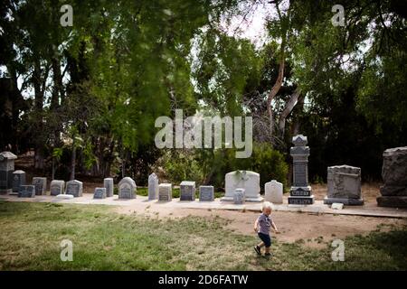 Two Year Old Running Through Park with Gravestones in Background