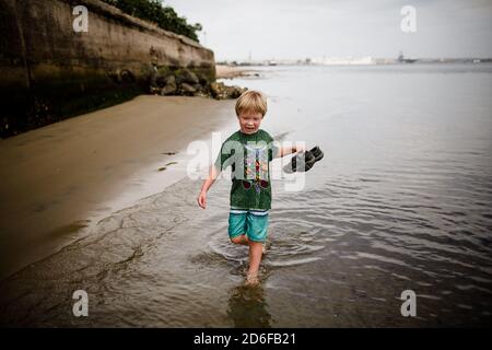 Six Year Old Boy Holding Sandals Running in Coronado Bay Stock Photo