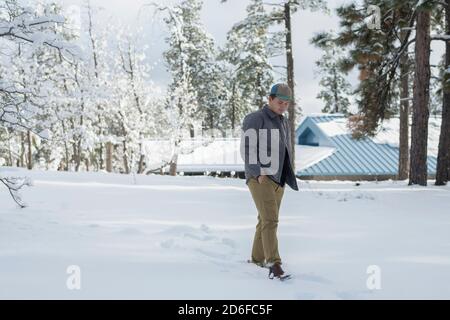 Young man walking through freshly fallen snow in a forested area Stock Photo