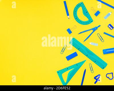 Back to school, education concept. Blue school tools stationery accessories, rubber; paper clips, eraser, pen and pencils, compass isolated on yellow Stock Photo