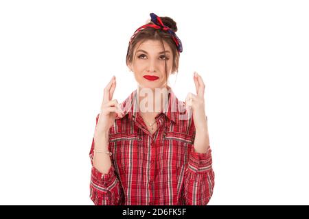 Wishing something badly. Happy pretty woman eager to win competition, keeps fingers crossed as waits for results, poses in studio isolated on white ba Stock Photo