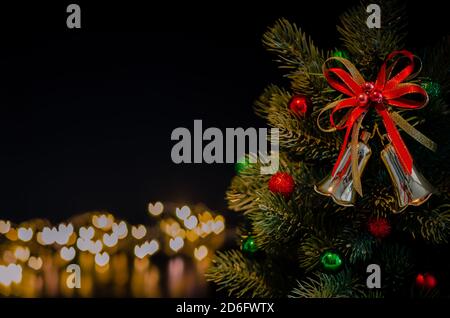 The bell ornaments decorate on Christmas tree with love shape bokeh lights background. Christmas and New year concept. Stock Photo