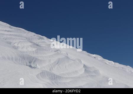 Diagonal patterns in snow ridge against blue sky Stock Photo