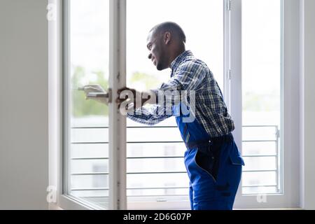 Young African Repairman In Overalls Installing Window Stock Photo