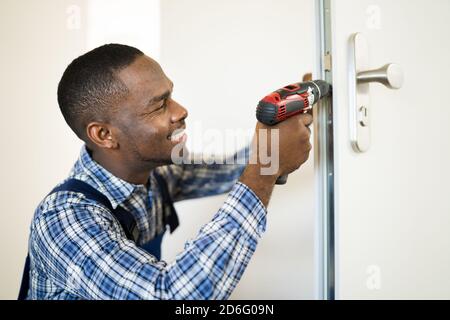 African Locksmith Man Changing And Fixing Door Lock Stock Photo
