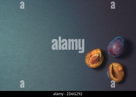 three ripe plums on a kitchen stone table isolated background pattern Stock Photo
