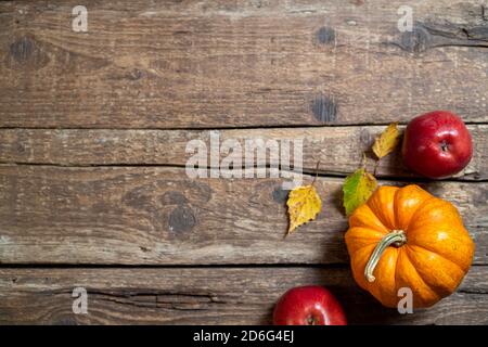 Autumn composition for Thanksgiving day. Pumpkin, fruits apples, autumn leaves on rustic wooden table. Fall seasonal decoration. Autumn background. To Stock Photo