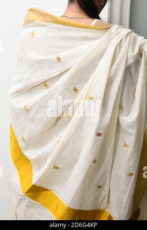 Indian silk sari, handmade white Kerala Sari, woman wearing holding sari, traditional wear on Onam festival, Vishu, wedding in India. multi-colored Stock Photo