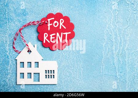 House for rent label on christmas holidays. Wooden house symbol with rent tag on blue background. Real estate, rental housing, rent for winter holiday Stock Photo