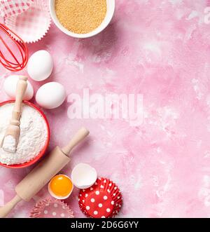 Baking background. Food ingredients for baking flour, eggs, sugar on pink background flat lay. Baking or cooking cakes or muffins. Long format with co Stock Photo
