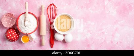 Baking background. Food ingredients for baking flour, eggs, sugar on pink background flat lay. Baking or cooking cakes or muffins. Long format with co Stock Photo