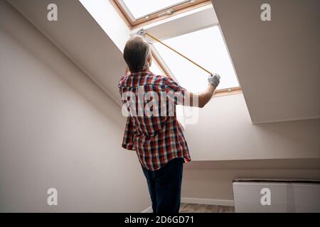 Rear view of repairman measuring skylight window Stock Photo