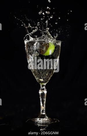 Wineglass with splash and lime. Stock Photo