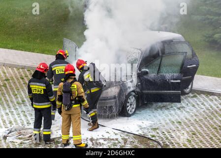 Warsaw, Poland - July 7, 2020: Fire brigade, putting out a burning car. Puffs of smoke near the car. Car fire in the parking lot. Firemen put out the Stock Photo